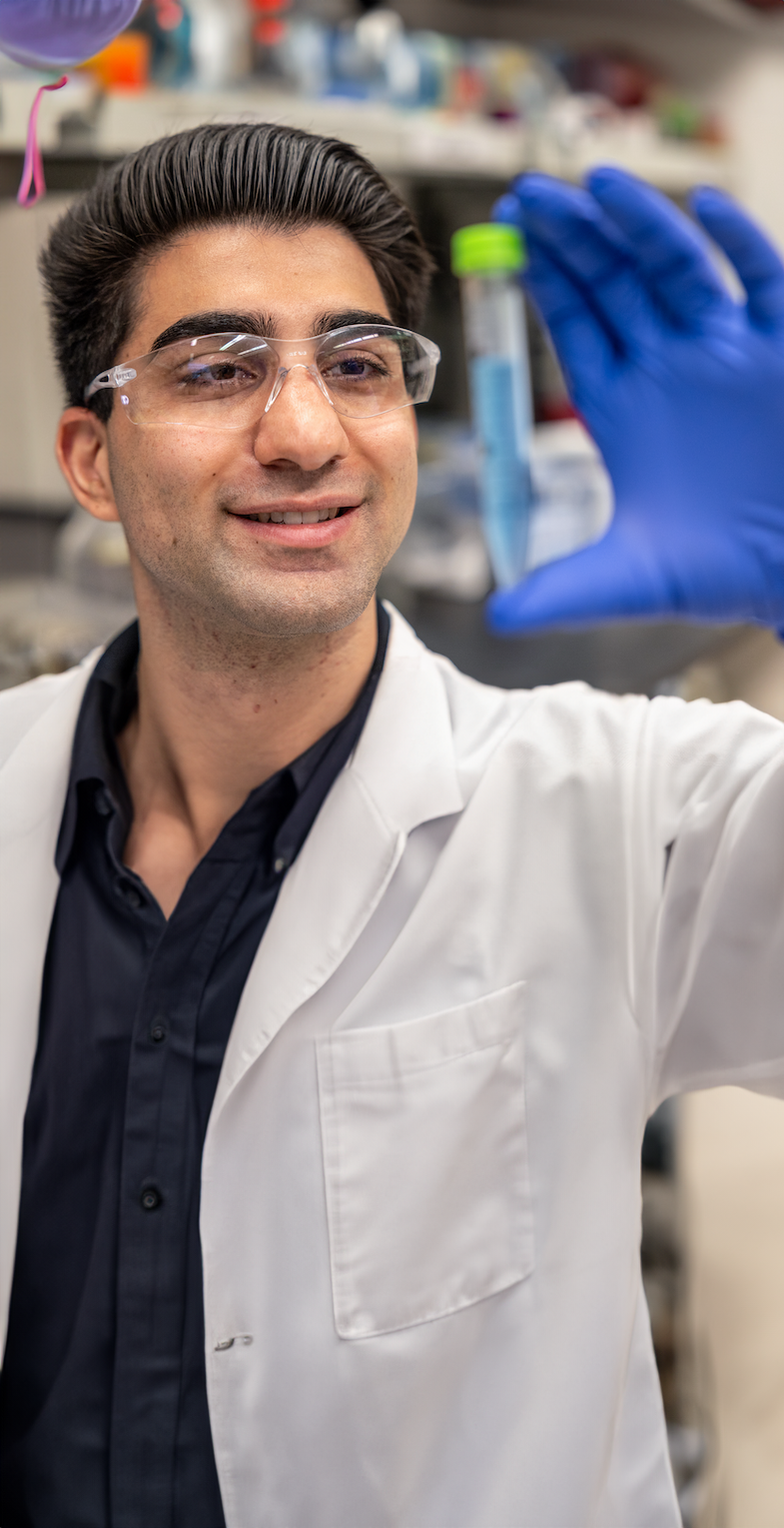 A-S-U professor in a lab coat holding a flask containing a blue liquid
