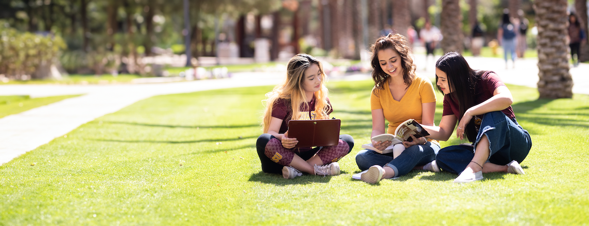 A-S-U students sitting in a grassy area on campus