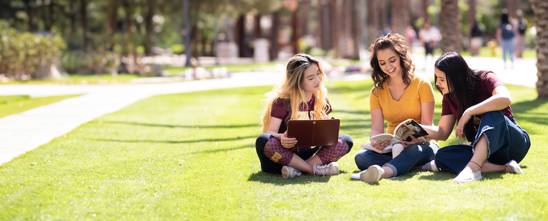 A-S-U students sitting in a grassy area on campus