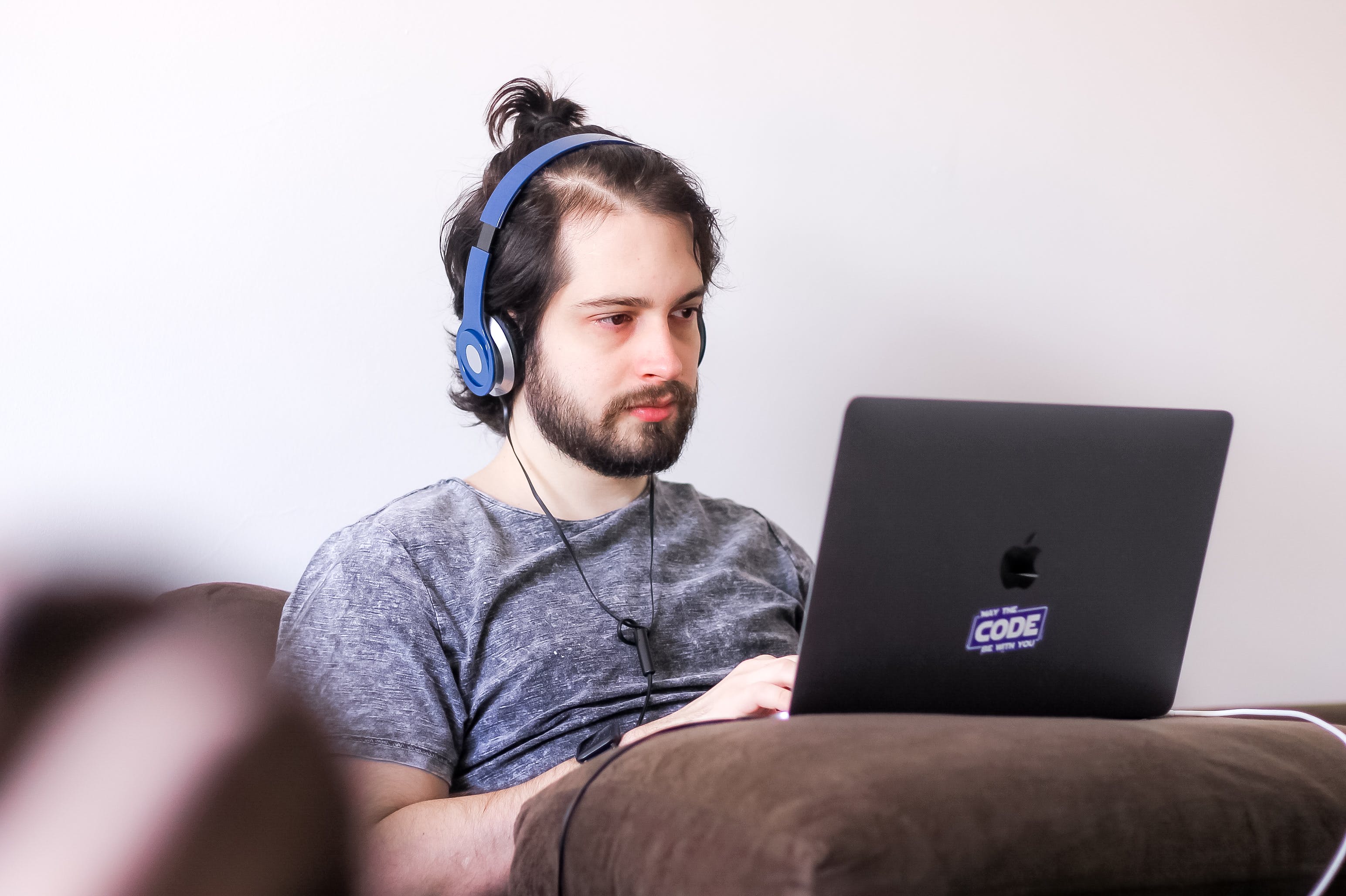 Man sitting in front of his laptop while wearing blue headphones