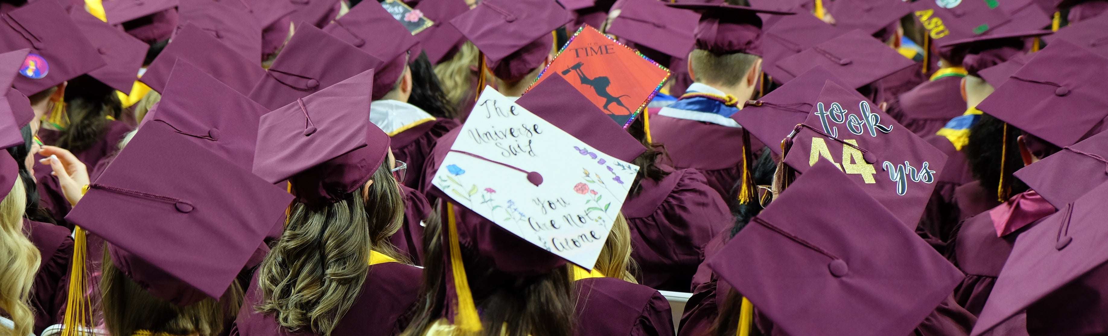Rearview of new graduates at a graduation ceremony wearing maroon