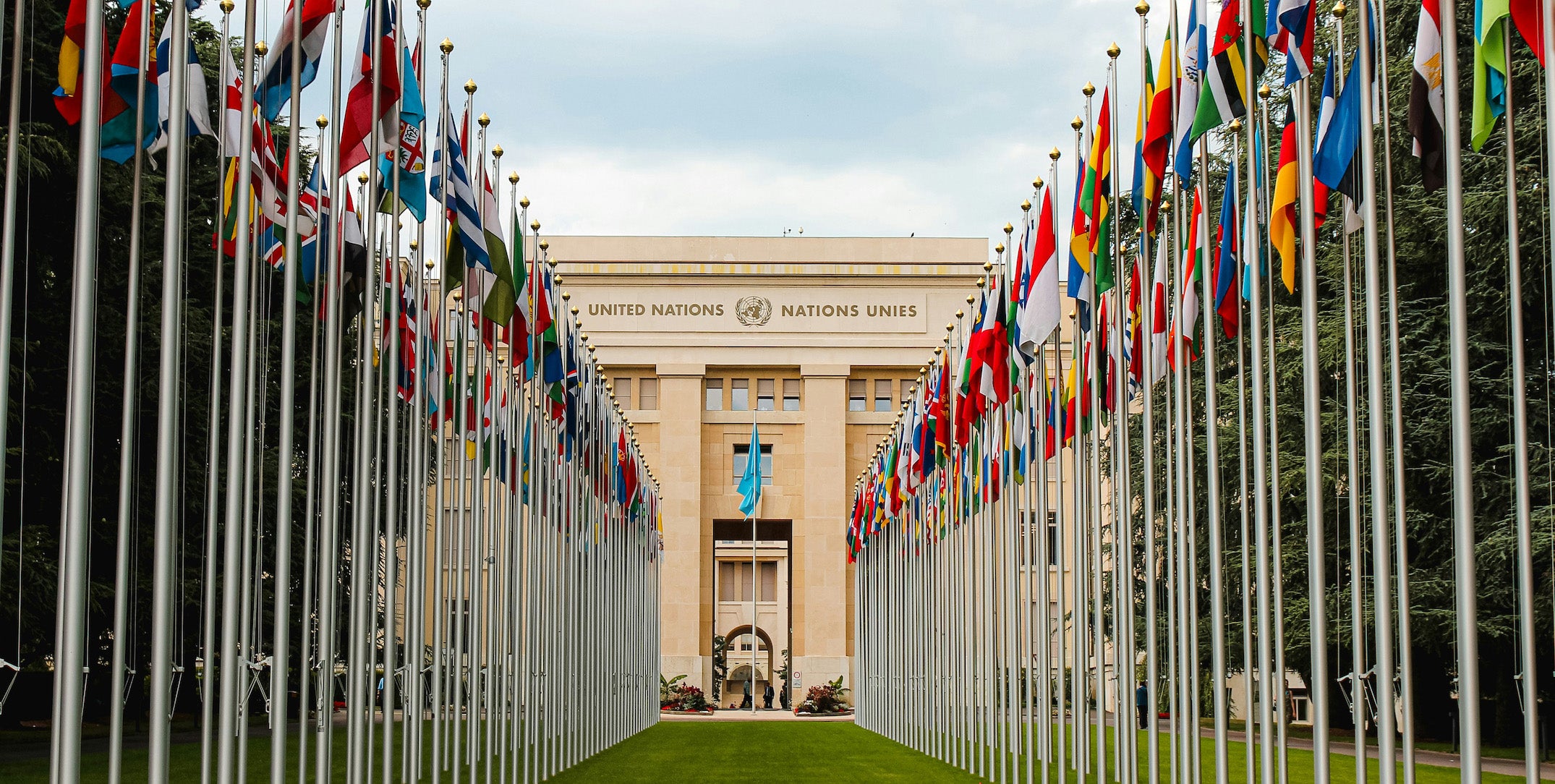 The united nations building in Switzerland, with many international flags in two rows in front
