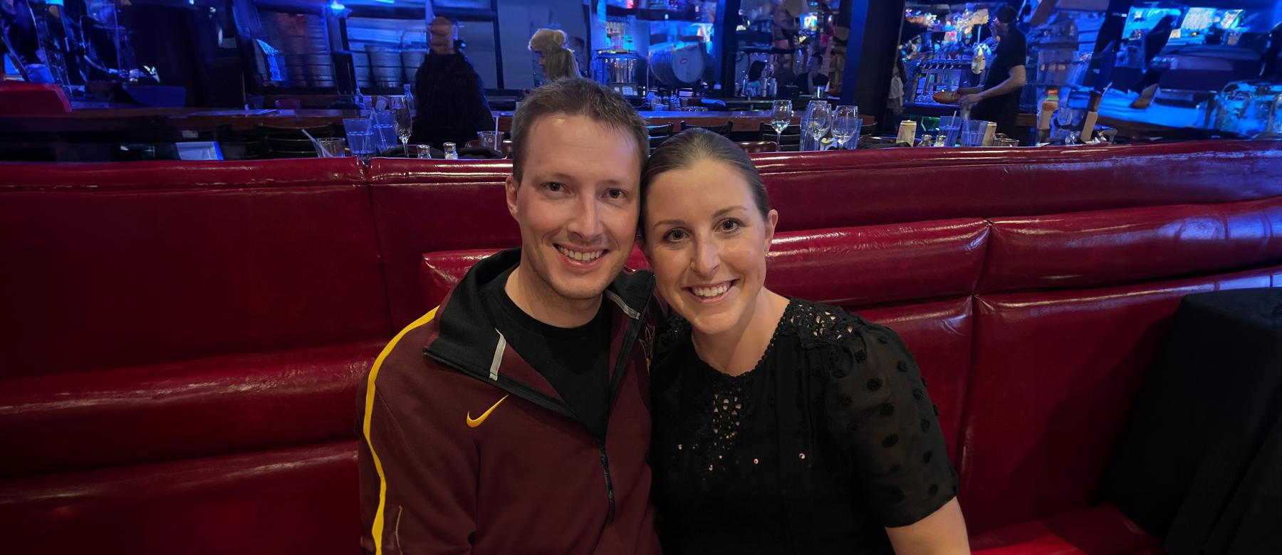 Kelly Weber Felch and her husband Ryan Felch, smiling and sitting at a maroon booth at a wood table