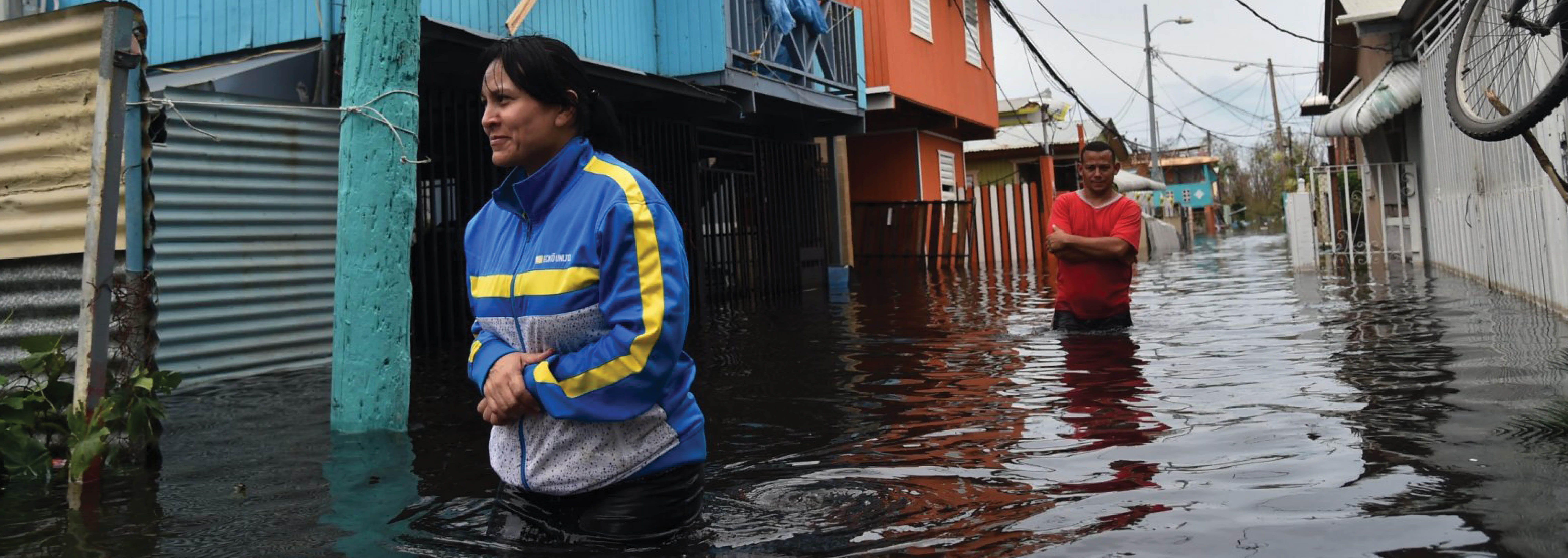 Two citizens from Puerto Rico wade through waist deep water that has flooded their street