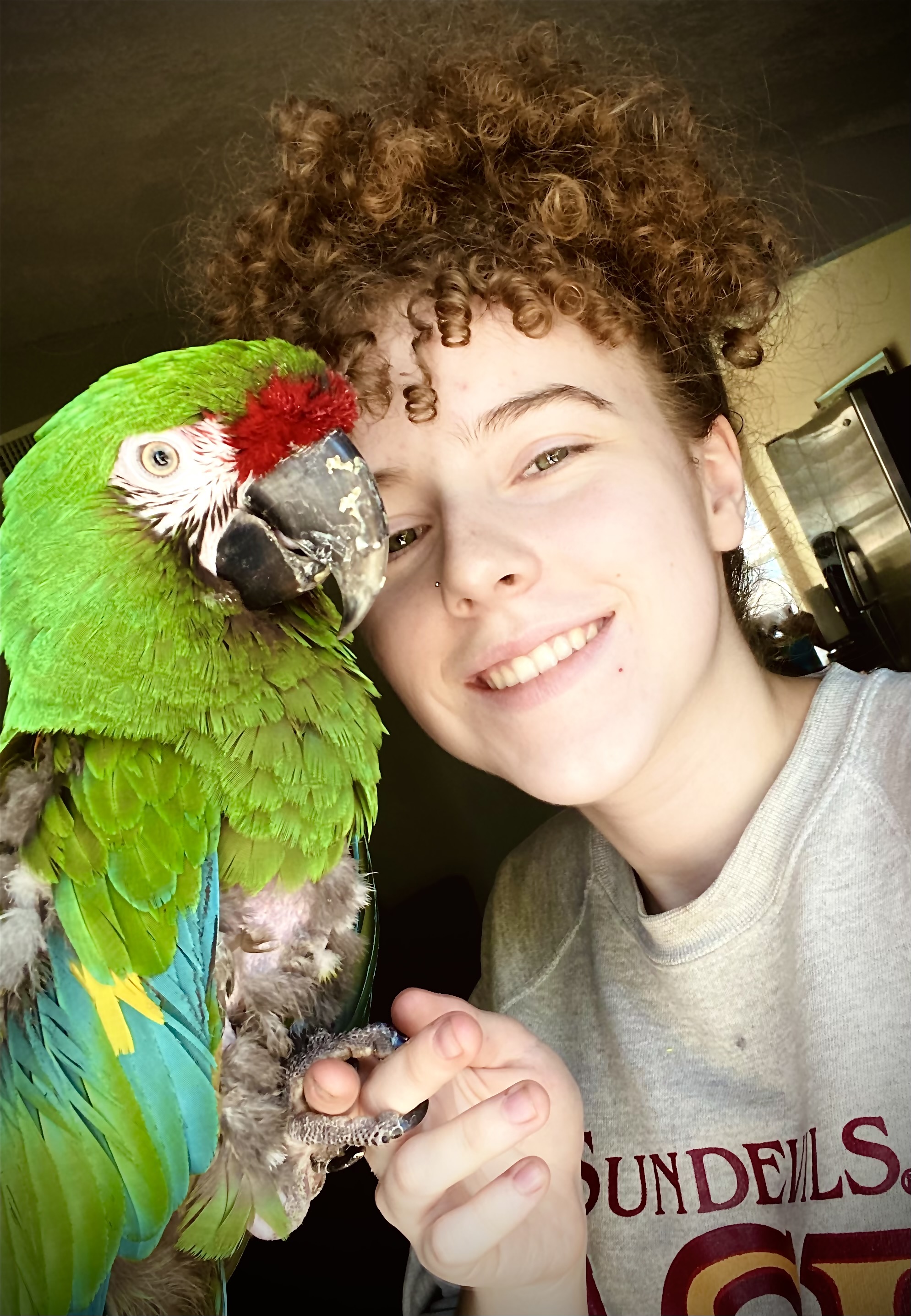 Emma poses with Harley. Emma has curly hair and Harley is snuggling up to her face.