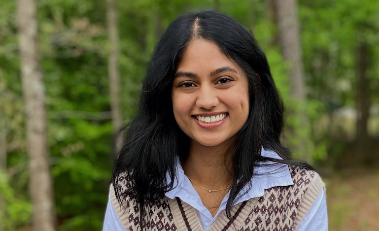 Woman smiling in front of wooded background