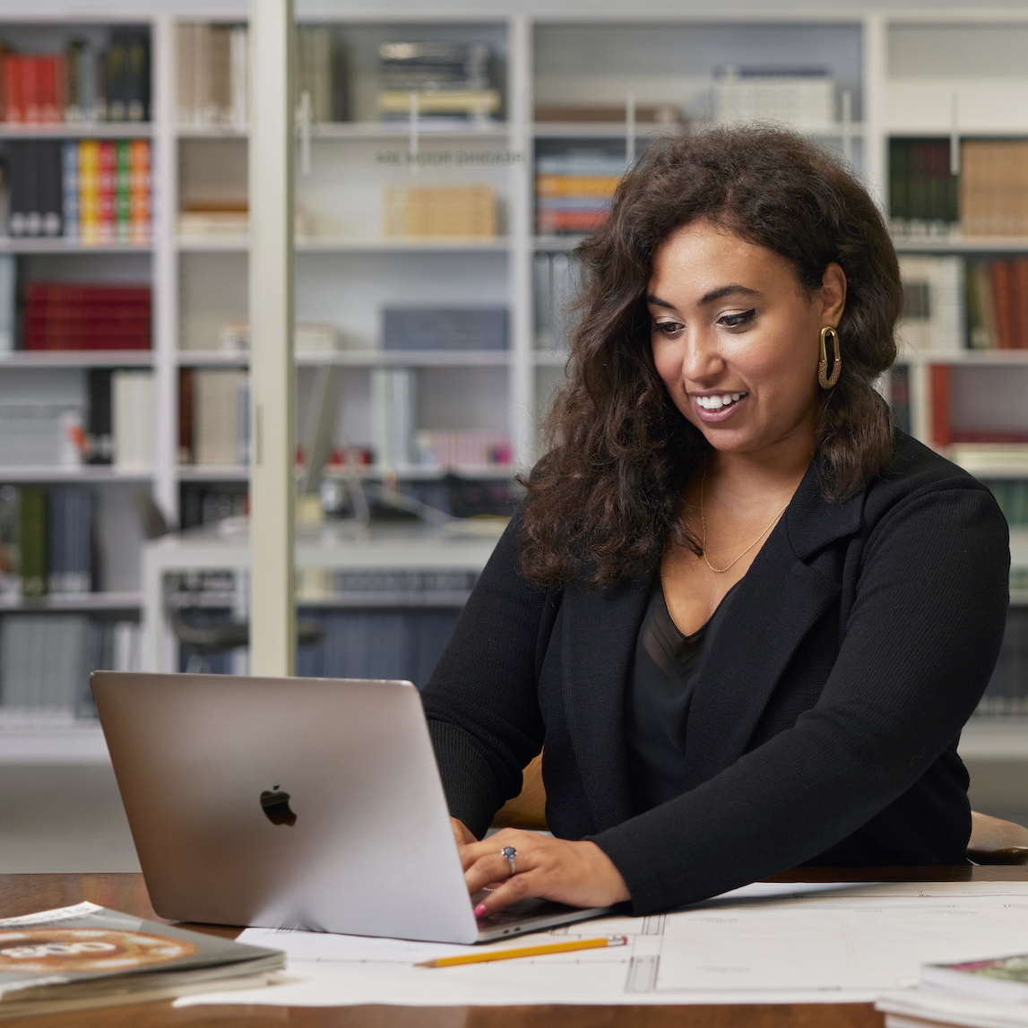 Woman in professional clothing sitting at a desk with a laptop