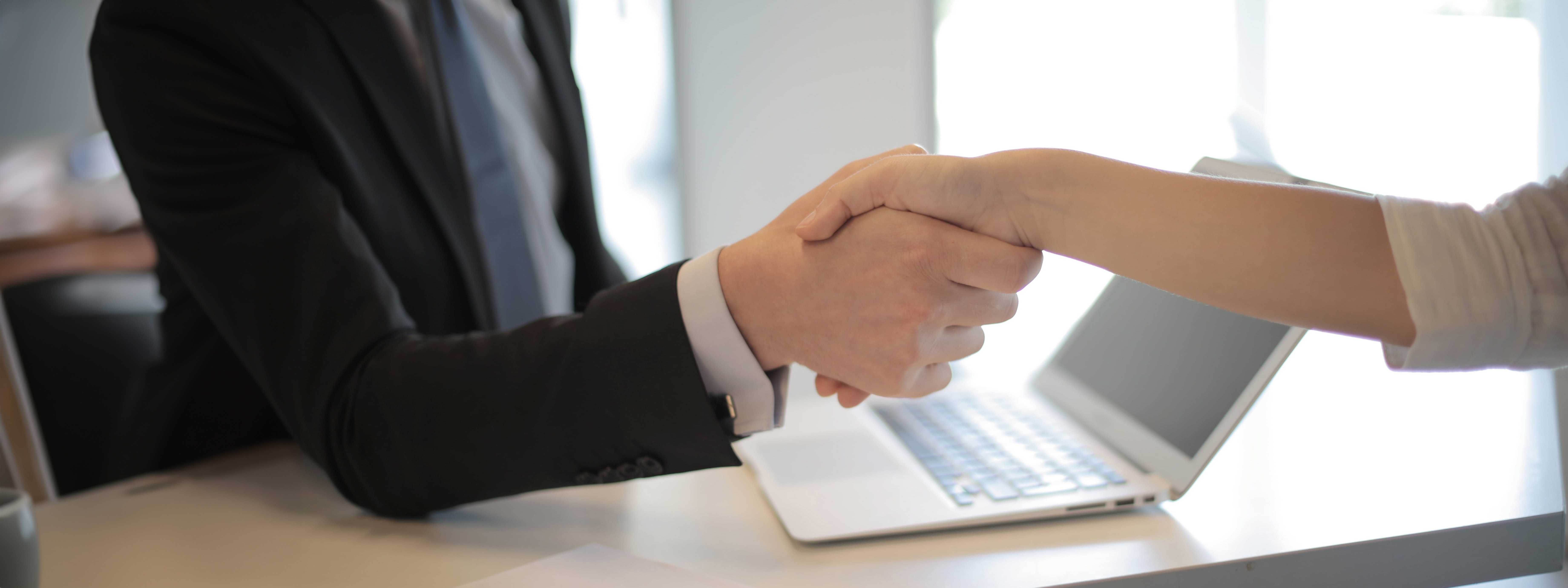 Two people with outstretched arms shaking each others hands