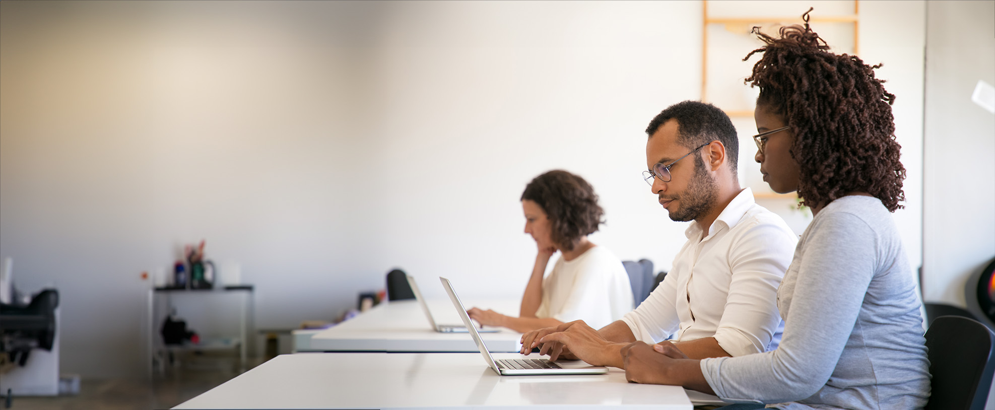 An instructor and trainee sitting at a table with their computers open
