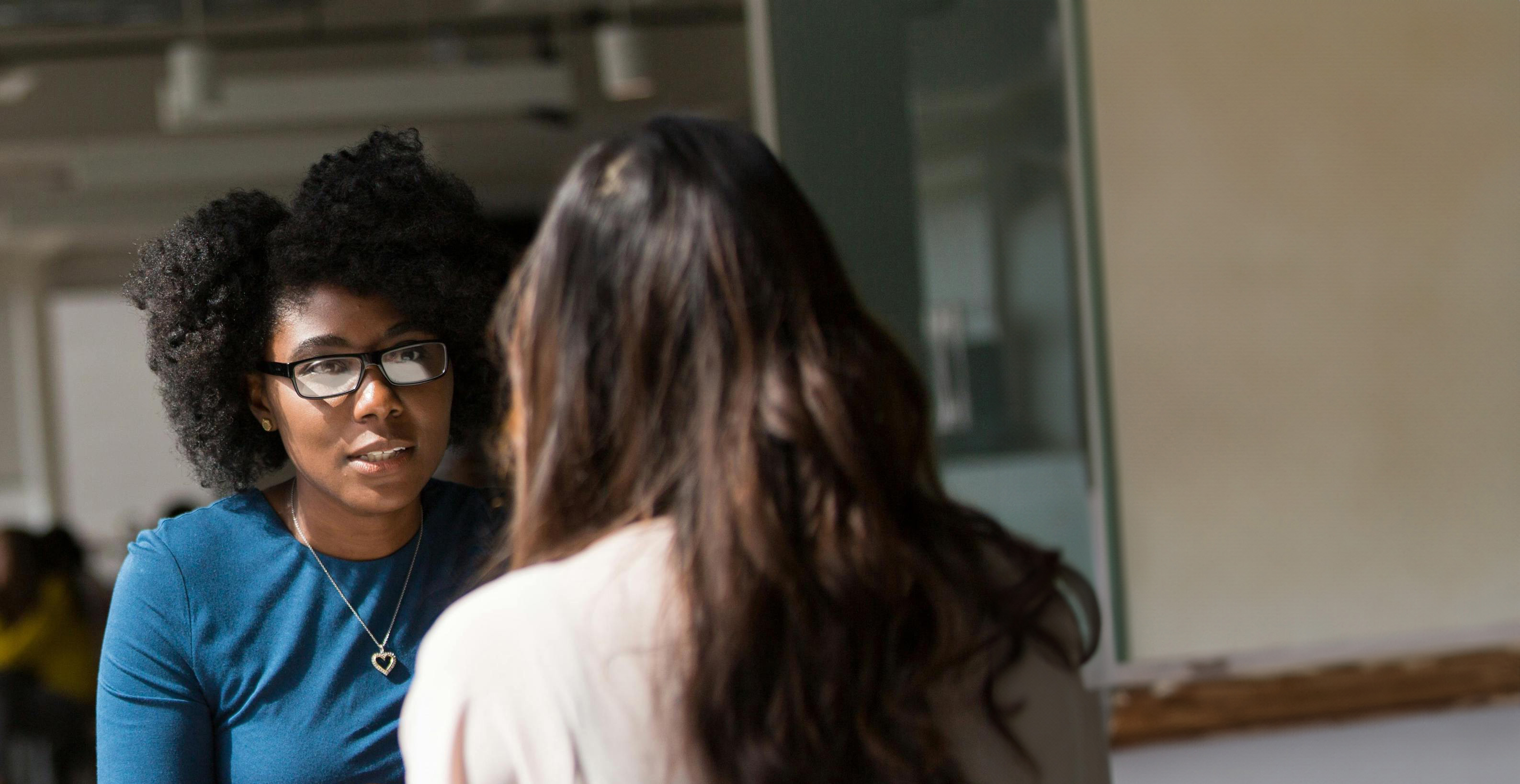 A counselor sitting at a table chatting with her client