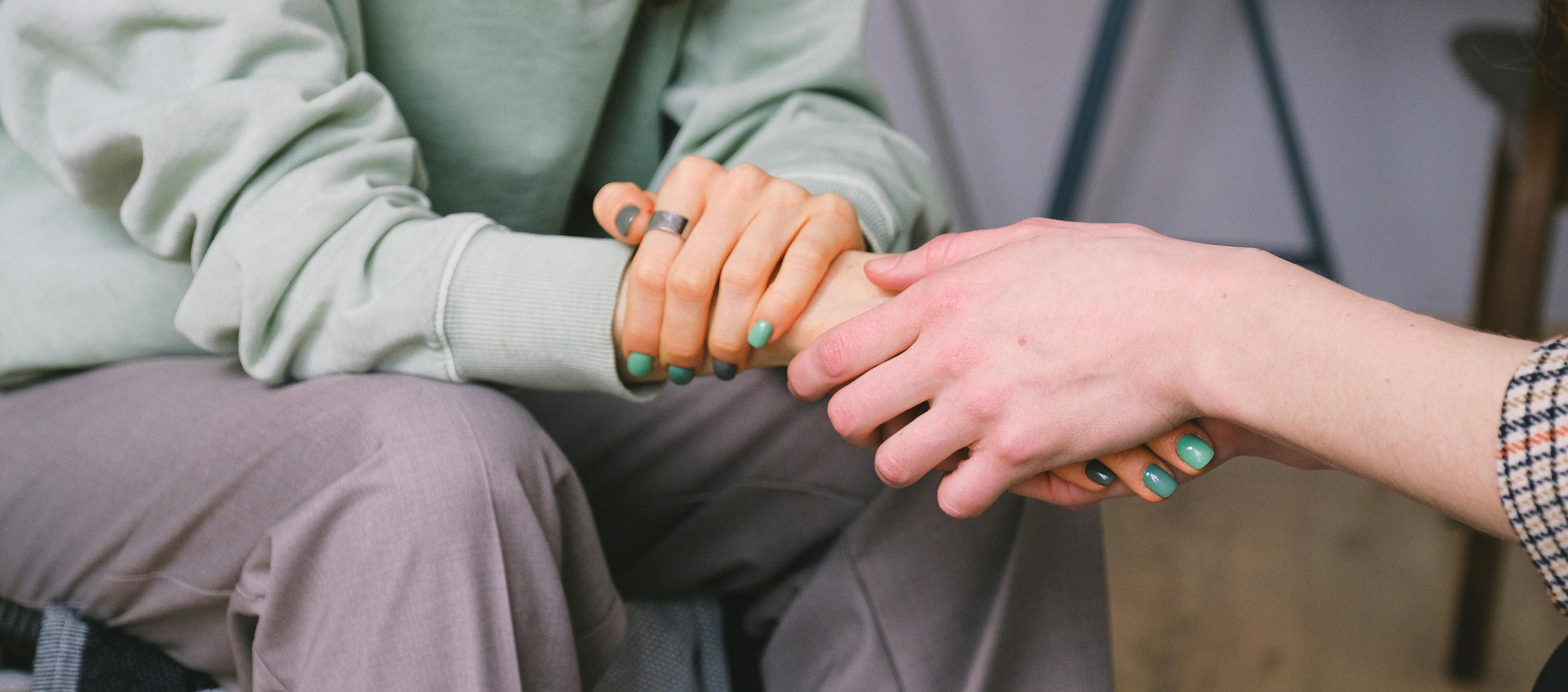 Two people's arms reaching out to each other, with their hands holding each other in the middle