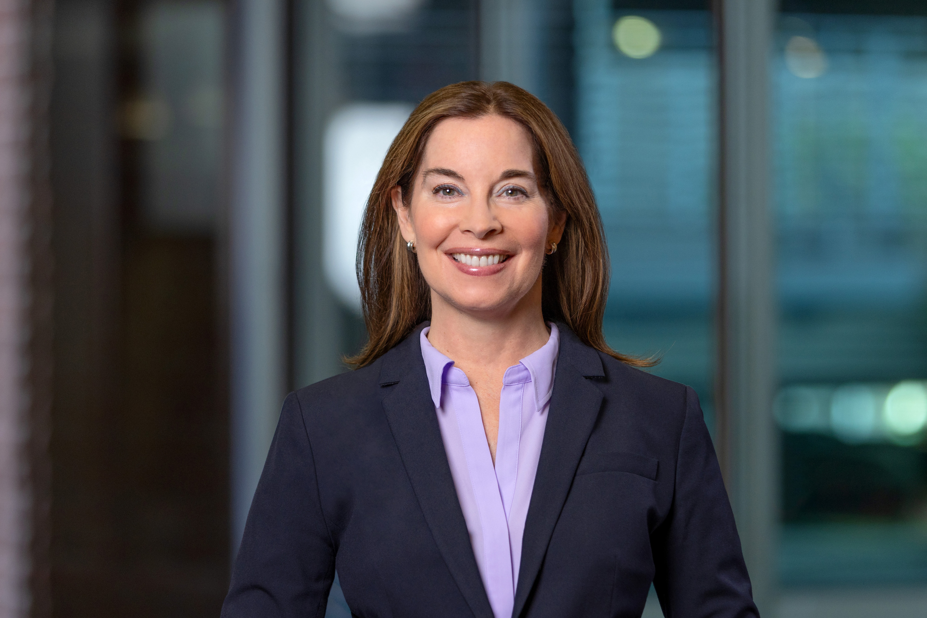 Woman with reddish hair wearing a blue blazer and smiling