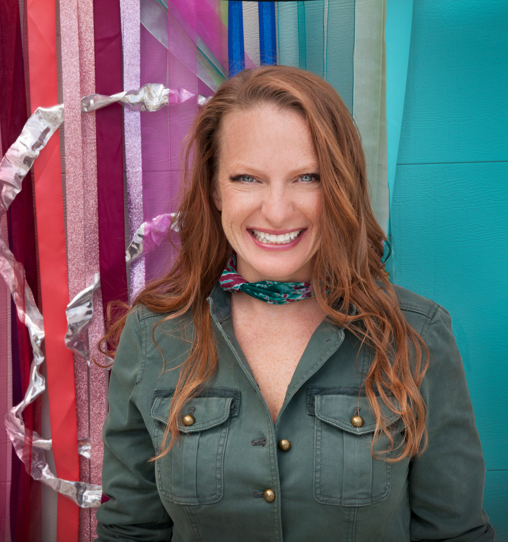 Smiling woman wearing a pink shirt and bright colored scarf