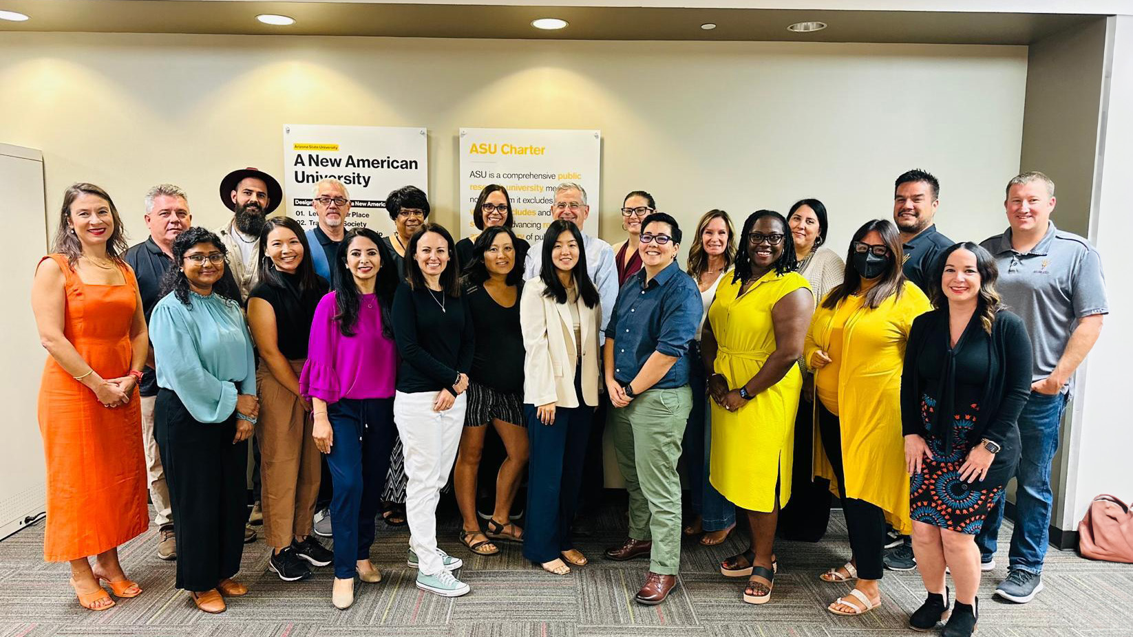 Group of School of Counseling and Counseling Psychology faculty members posing together indoors with ASU-related posters in the background.