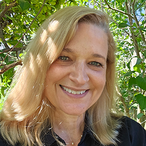 Portrait of Elizabeth Donaldson standing in front of a leafy background outside.