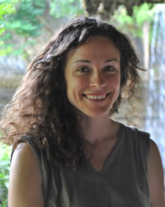 Jada Ach, smiling and wearing a brown shirt