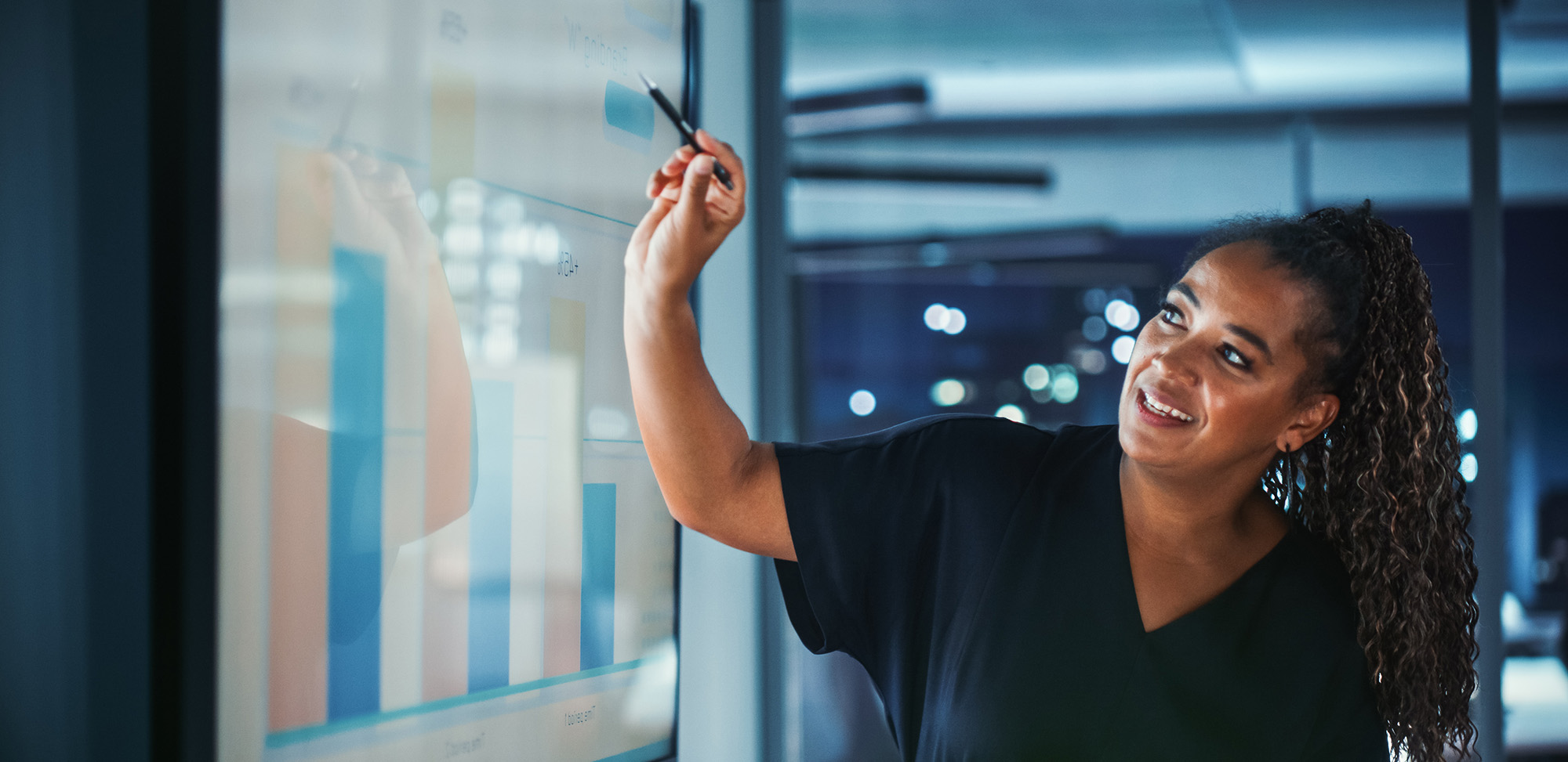 Woman pointing to a screen displaying charts and graphs