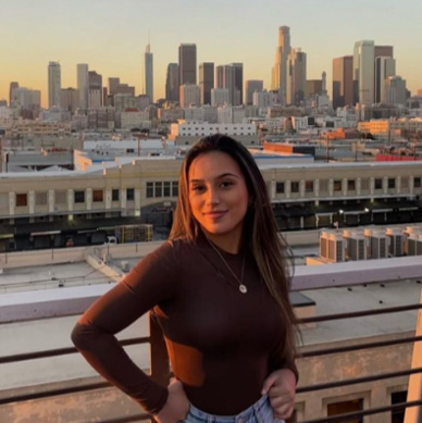 Shaye Pua, a young woman with long hair on a rooftop with a cityscape in the background.