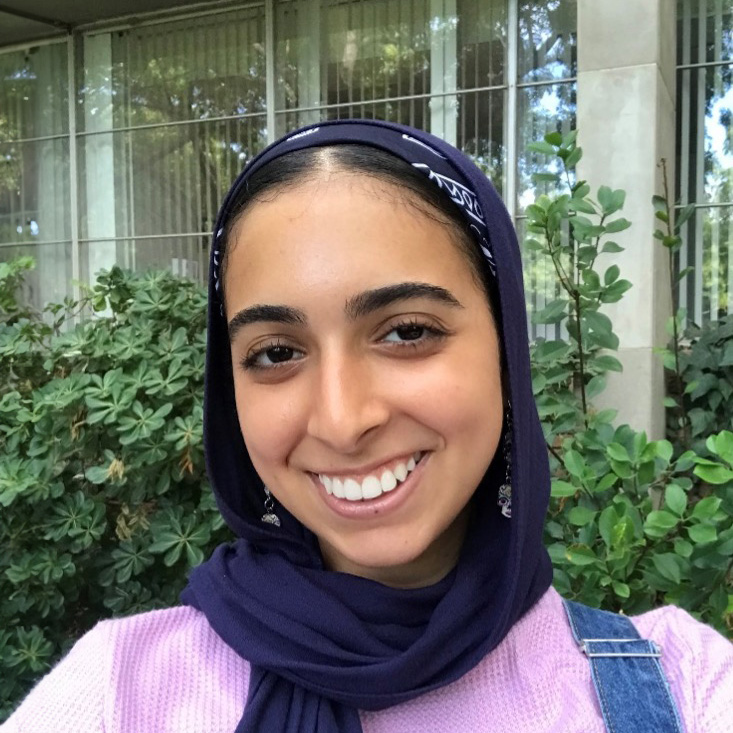 Hana Roushdy, a young woman wearing a pink shirt and smiling.